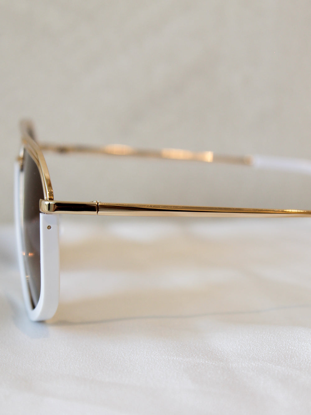 White frame aviator sunglasses with gold accents and arms