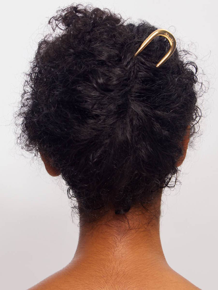 Woman with curly hair updo styled with a gold french hair clip