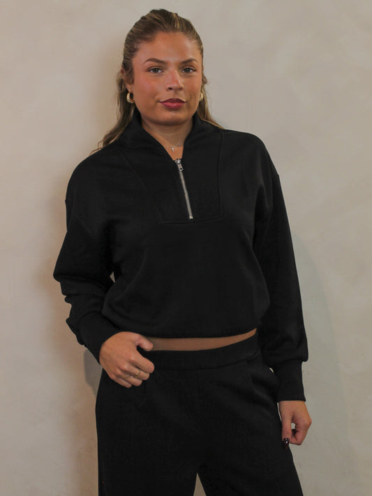 Black sweatshirt with a quarter zip detail.