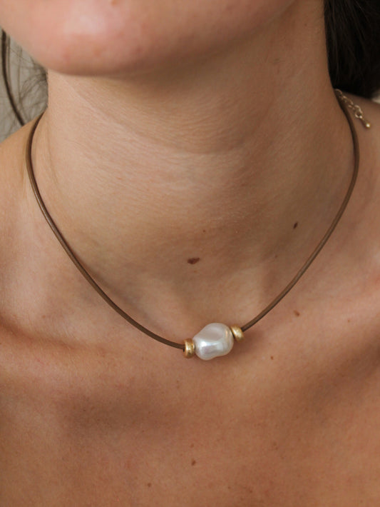 Necklace with a pearl pendant on a person's neck