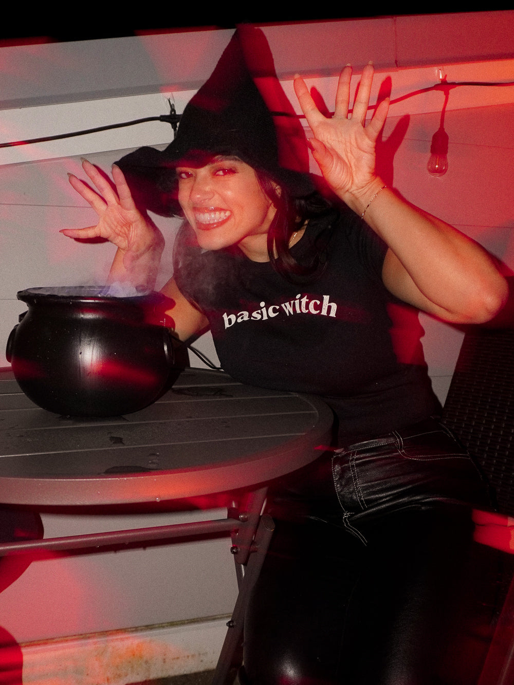 Woman wearing a black tee that says basic witch across the front for a halloween photoshoot