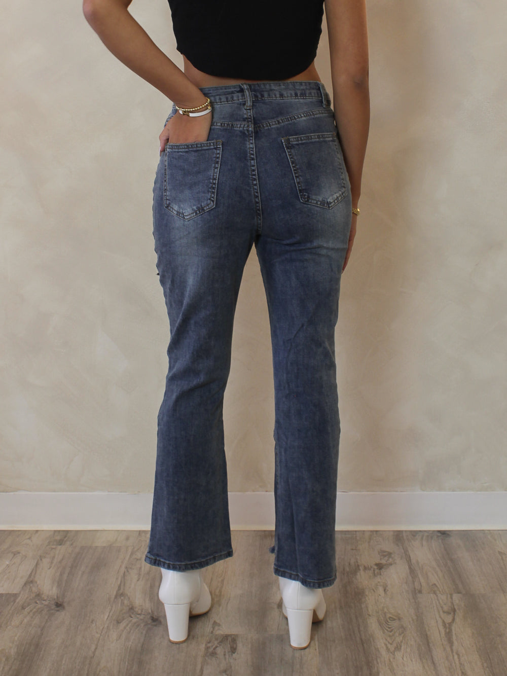 Woman wearing a pair of cropped, medium wash denim - back view