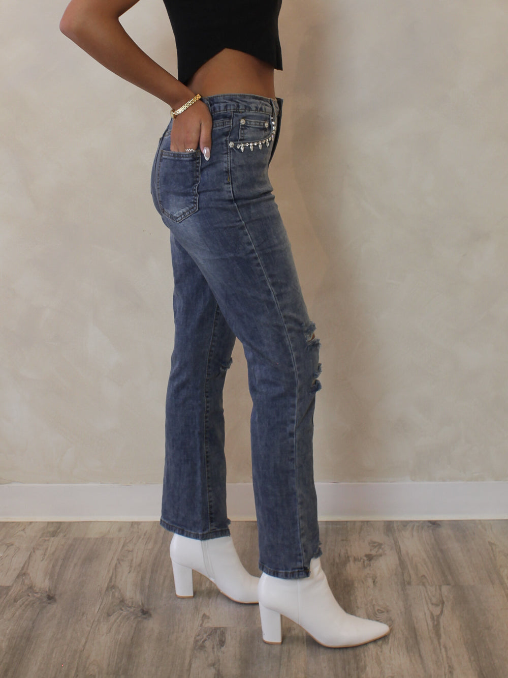 Woman wearing a pair of cropped, medium wash denim with cut out heart and rhinestone details