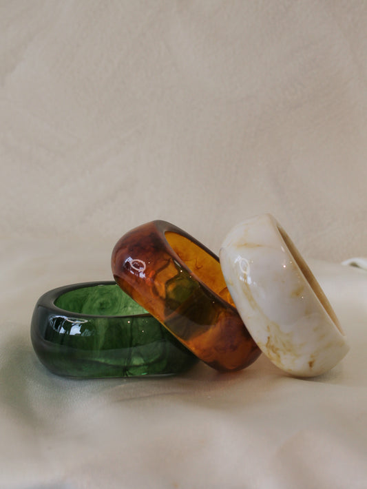 Three chunky, resin bangle bracelets in green, brown and ivory