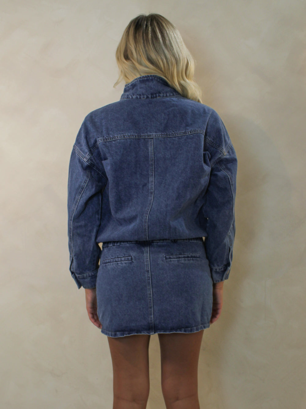 Back view of a long sleeve denim mini dress worn by a model.