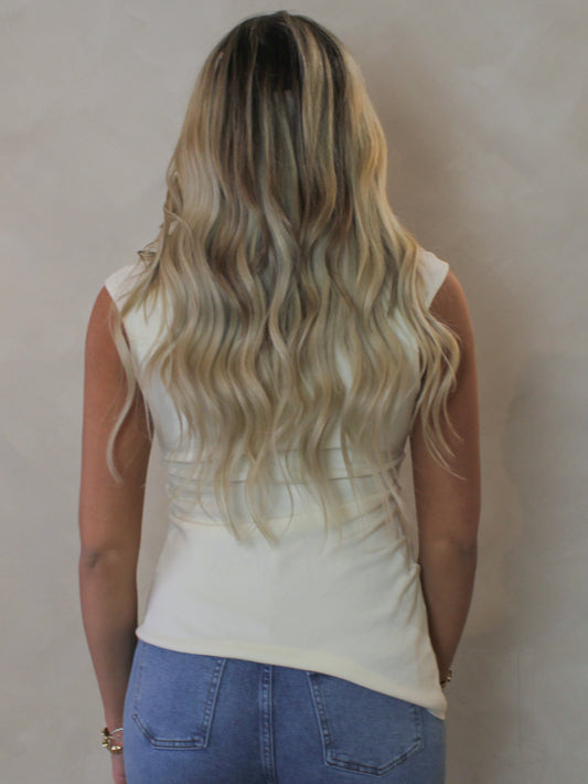 Model wearing an off white top with an asymmetric hemline