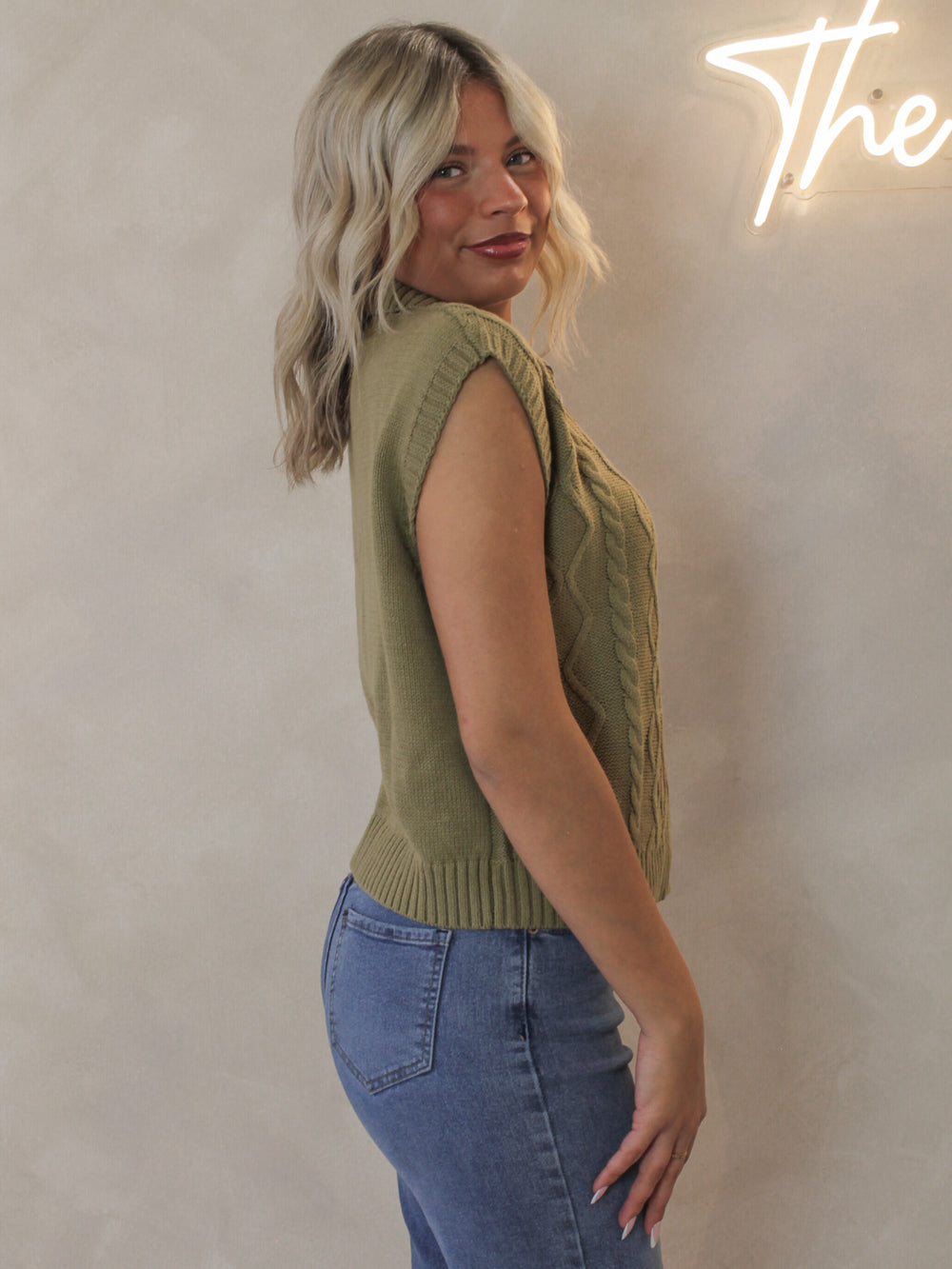 Woman wearing a sleeveless knit sweater with half zip detail