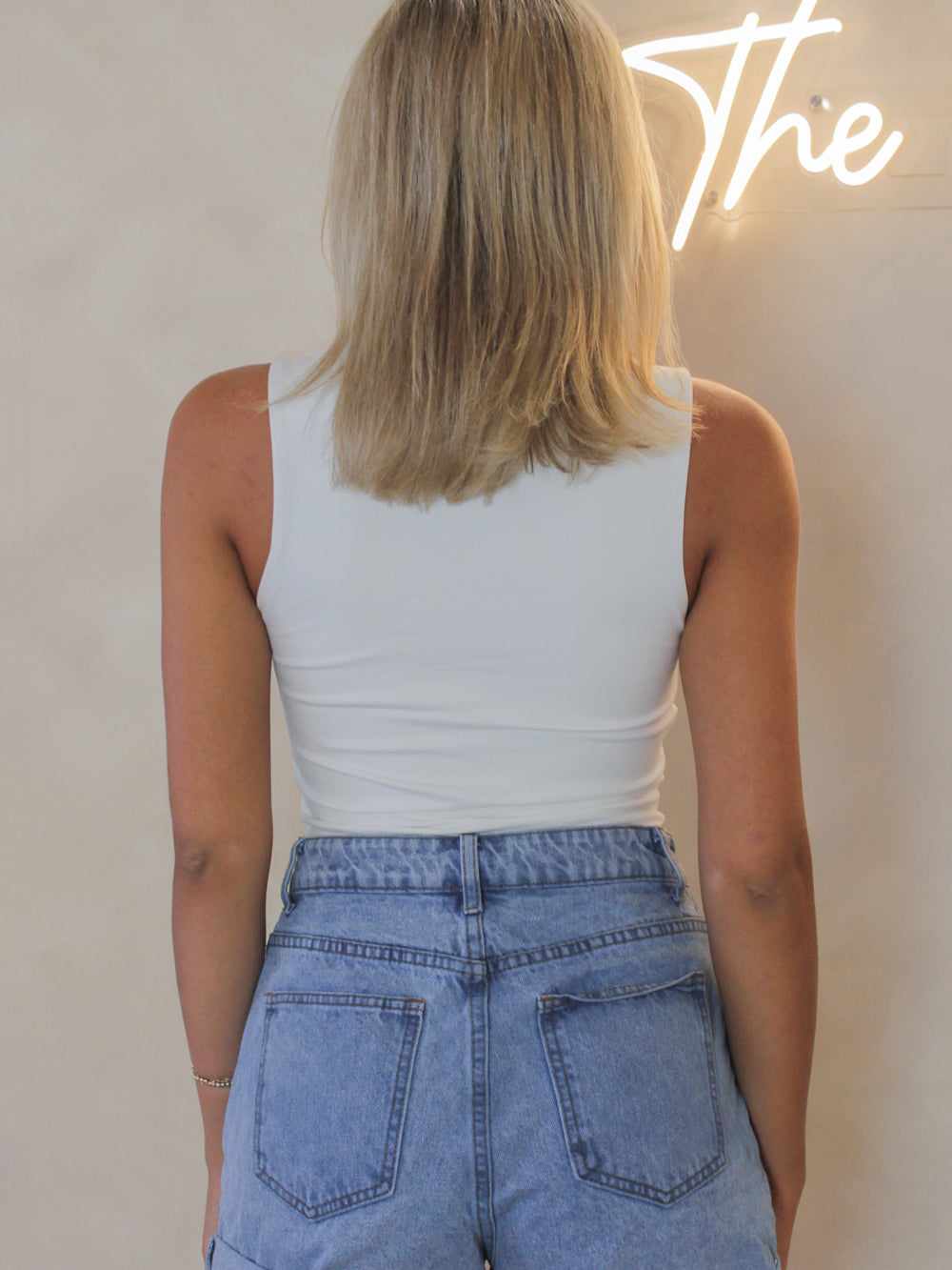 Back view of a sleeveless white bodysuit for women