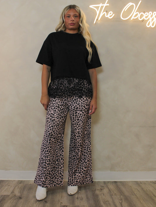 A woman wearing leopard pants outfit styled with a black lace t-shirt.