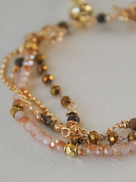 Close-up of a beaded bracelet with gold, neutral and pink beads