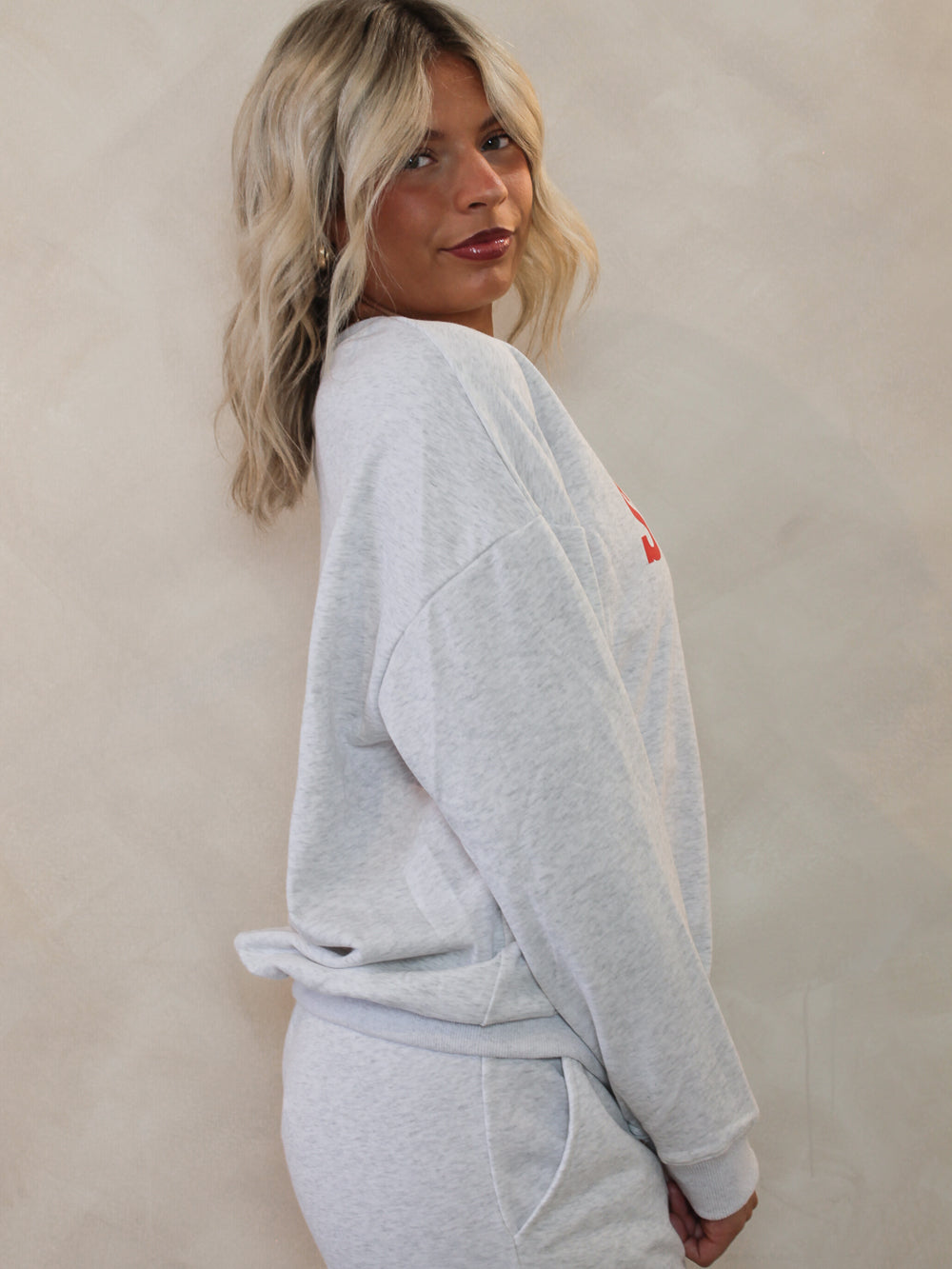 Person wearing a gray sweatshirt with a logo that says 'Sunday Coffee Club'