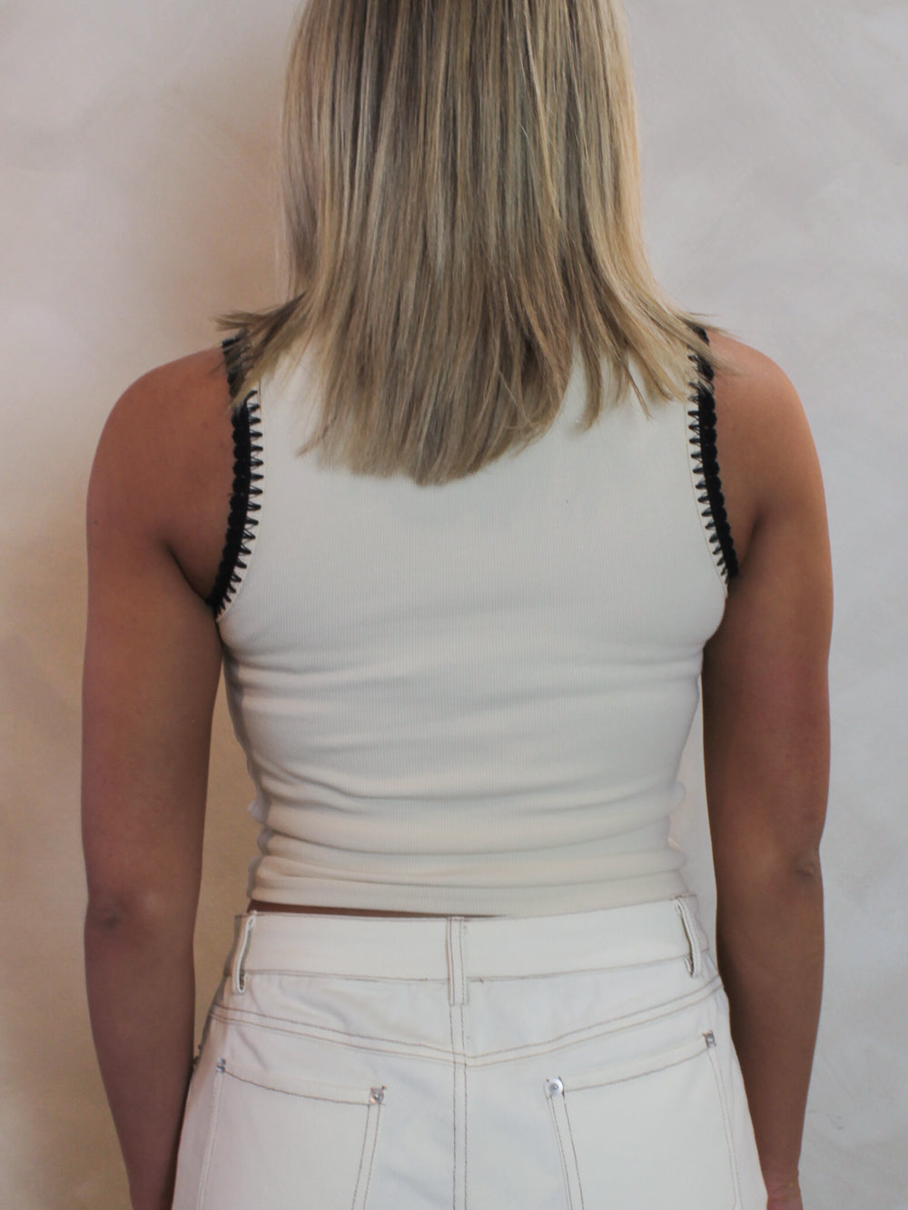 back view of a cream tank top with contrast black trim.