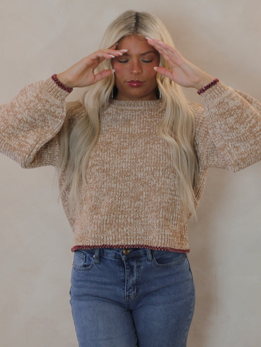 Woman wearing a beige sweater with red contrast hems