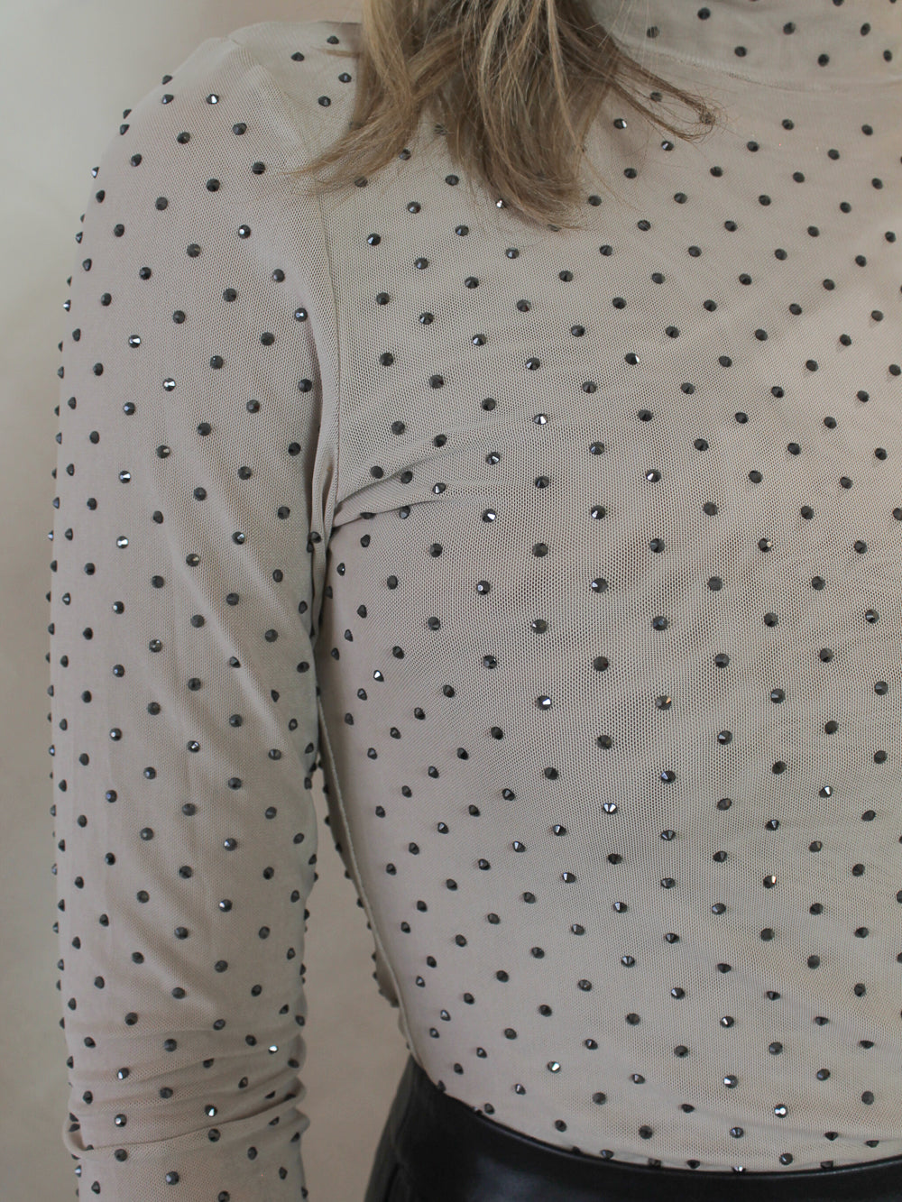 Close up shot of a light beige mesh top with silver sparkle embellishemnets all over