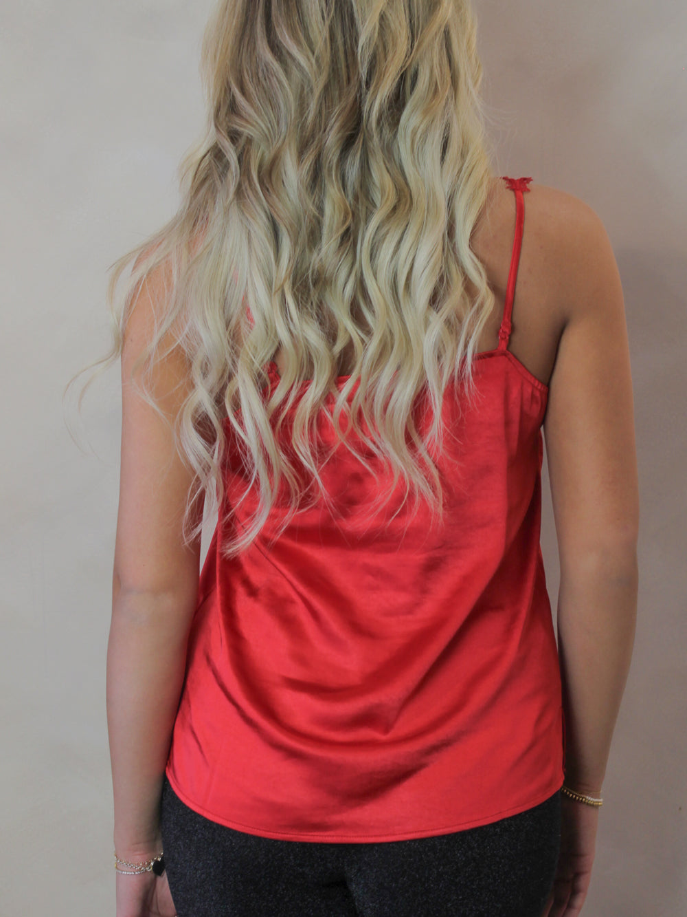 Back view of a red satin tank top on a model