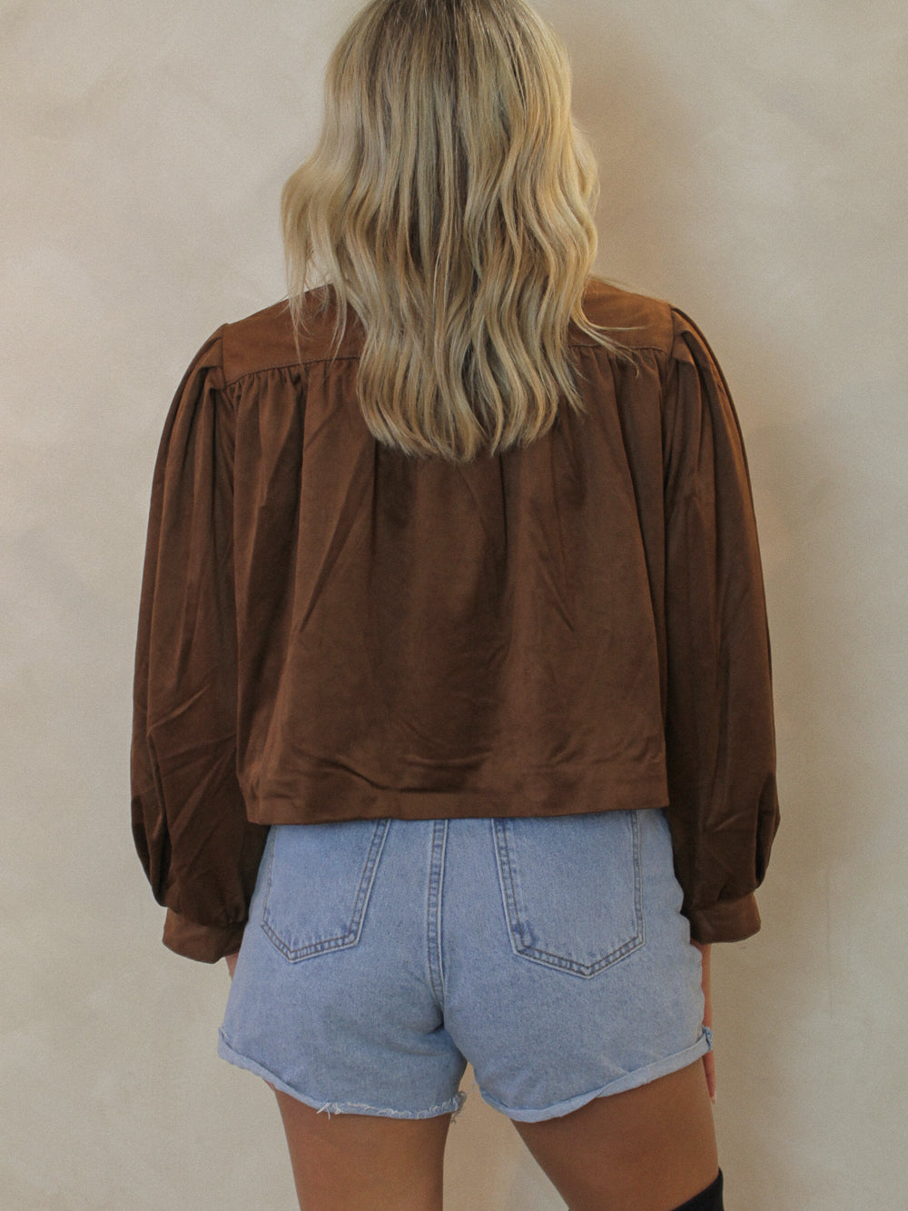 Person wearing a brown suede jacket and light blue shorts