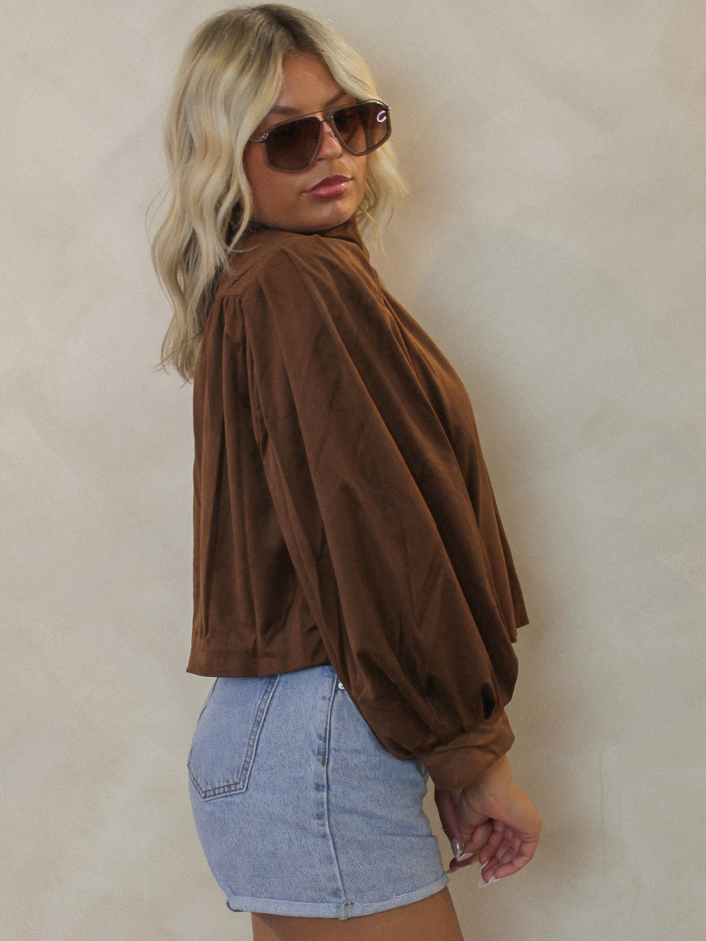 Woman wearing a brown Steve Madden suede jacket with pleated sleeves