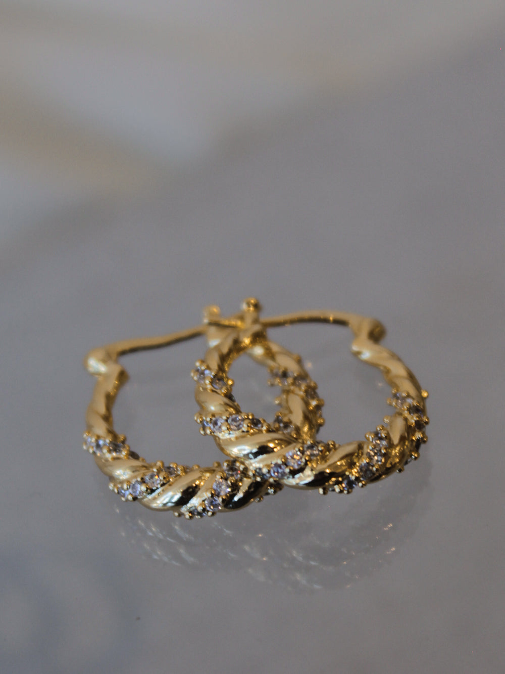 A pair of gold hoop earrings with a twist detail