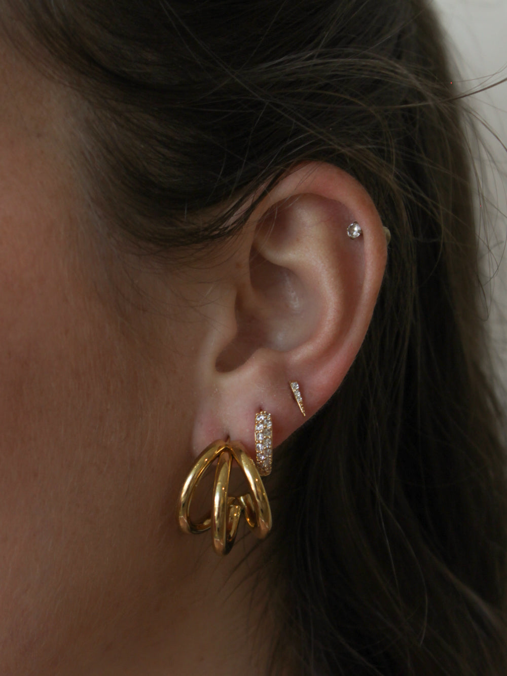 Close-up of an ear with gold and diamond earrings.