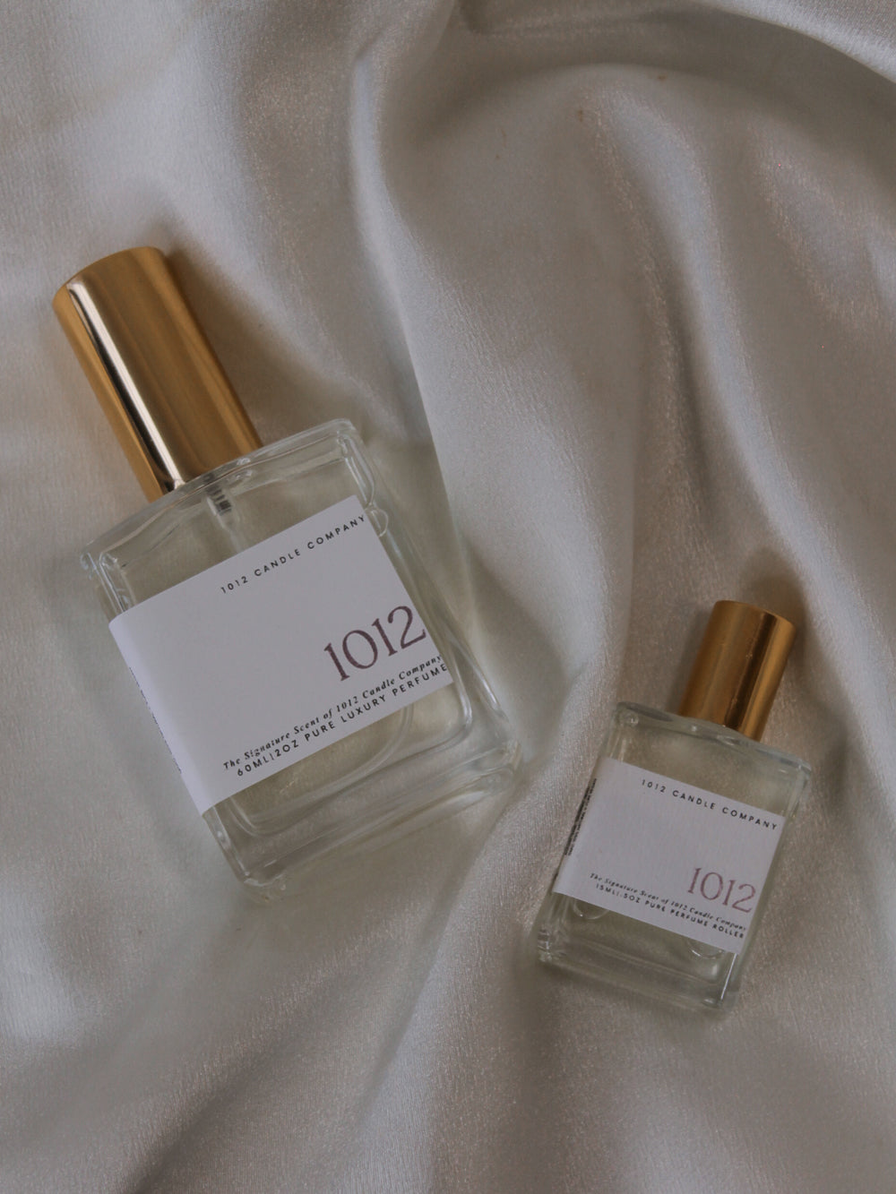Two perfume bottles by 1012 Candle Co with gold tops and with scents of yuzu, bergamot, grapefruit, cashmere and more