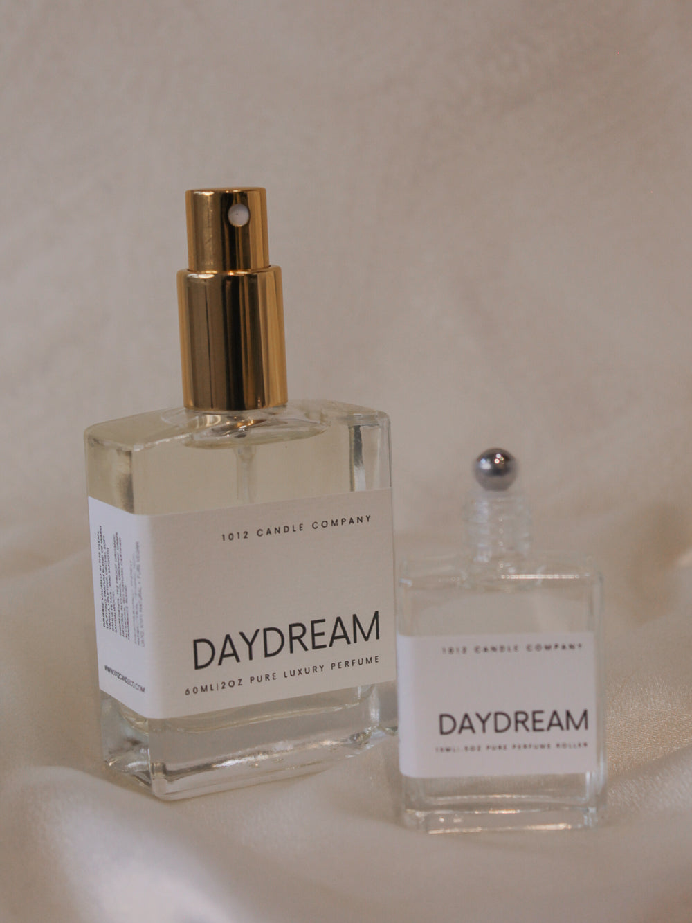 Two bottles of Daydream perfume by 1012 Candle Co in different size showing that one is a spray bottle and one is a rollerball 