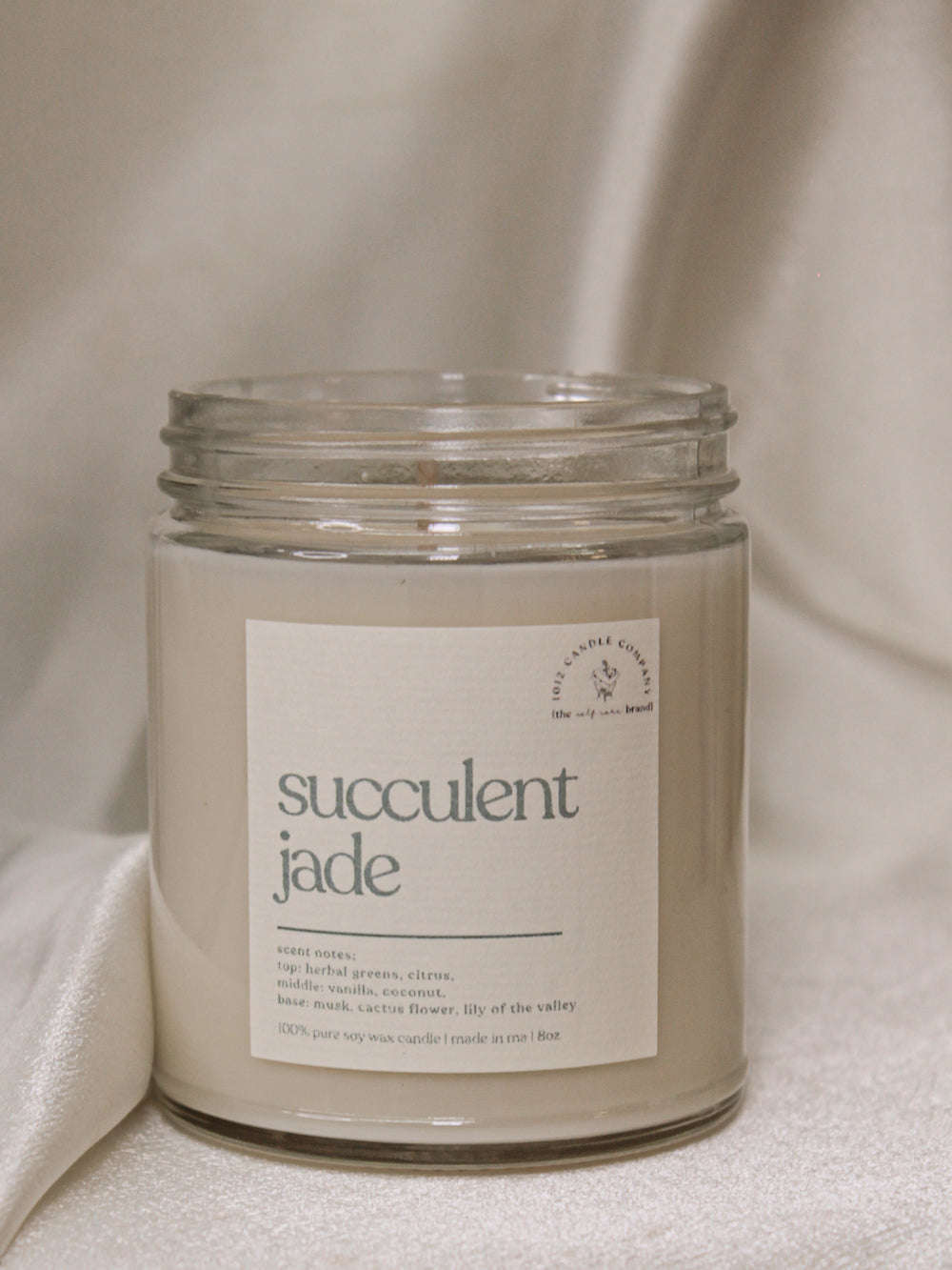 a candle labeled succulent jade in a clear glass vessel with screw on top 