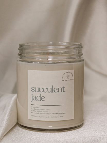 a candle labeled succulent jade in a clear glass vessel with screw on top 