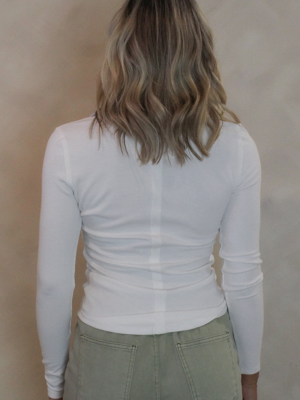 Back view of a white long sleeve top on a young woman