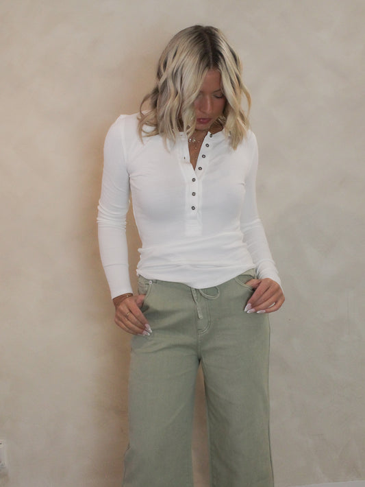 Woman wearing a white, ribbed long sleeve top paired with sage green denim for an everyday outfit.