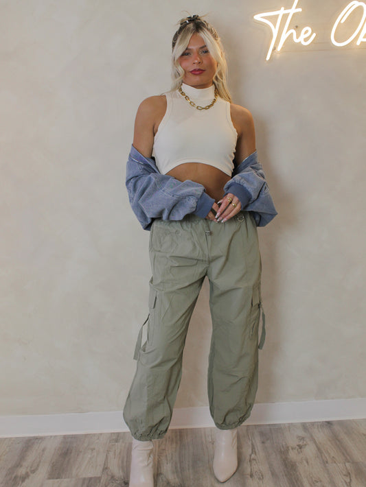 GIRL WEARING OLIVE JOGGER PANTS WITH A DENIM JACKET, CROP TOP AND GOLD JEWELRY