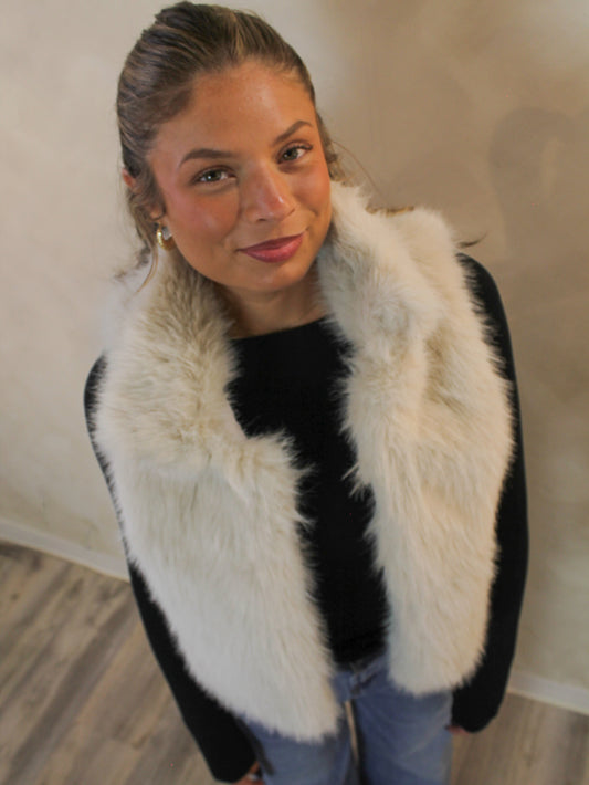 Cream fur vest styled with a black long sleeve top and jeans.