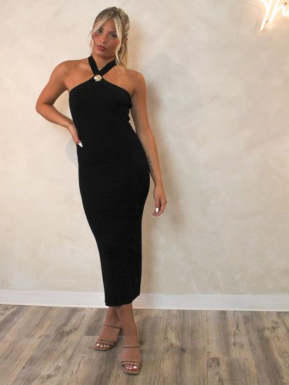 Model wearing a black ribbed dress with a criss cross neckline and seashell hardware