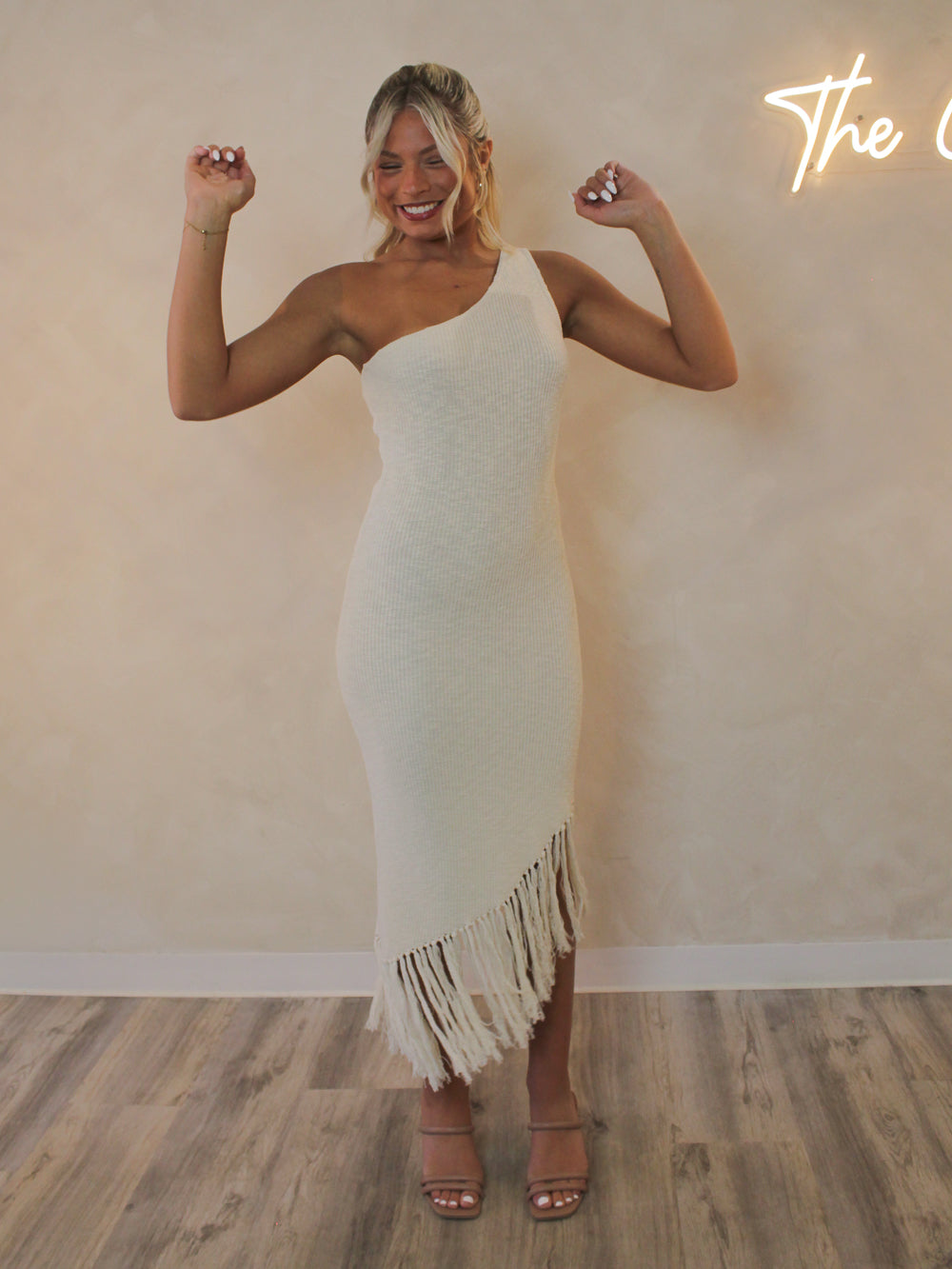 Woman wearing a one shoulder knit dress with a fringe bottom