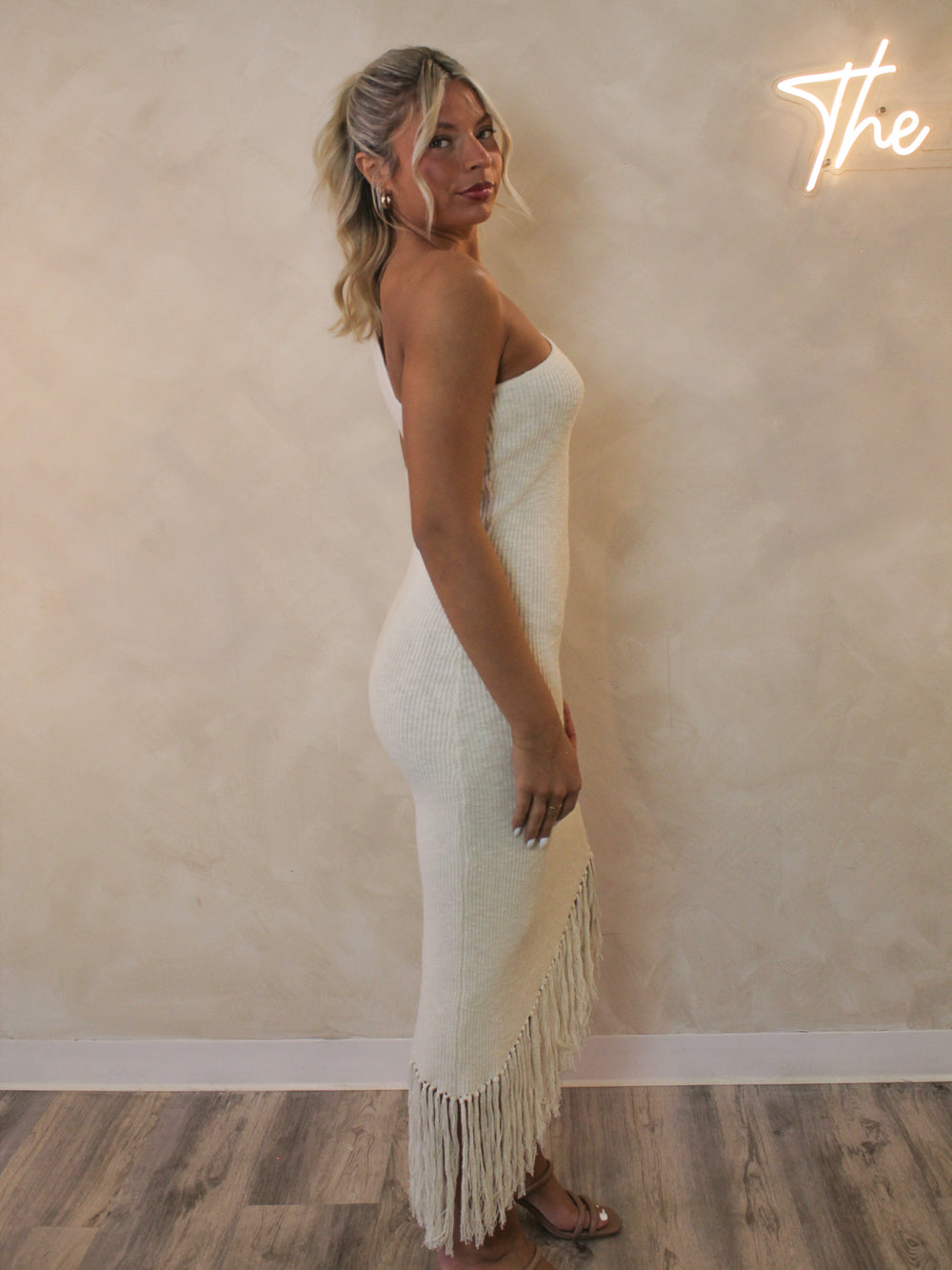 Woman wearing a one shoulder dress with a fringe bottom