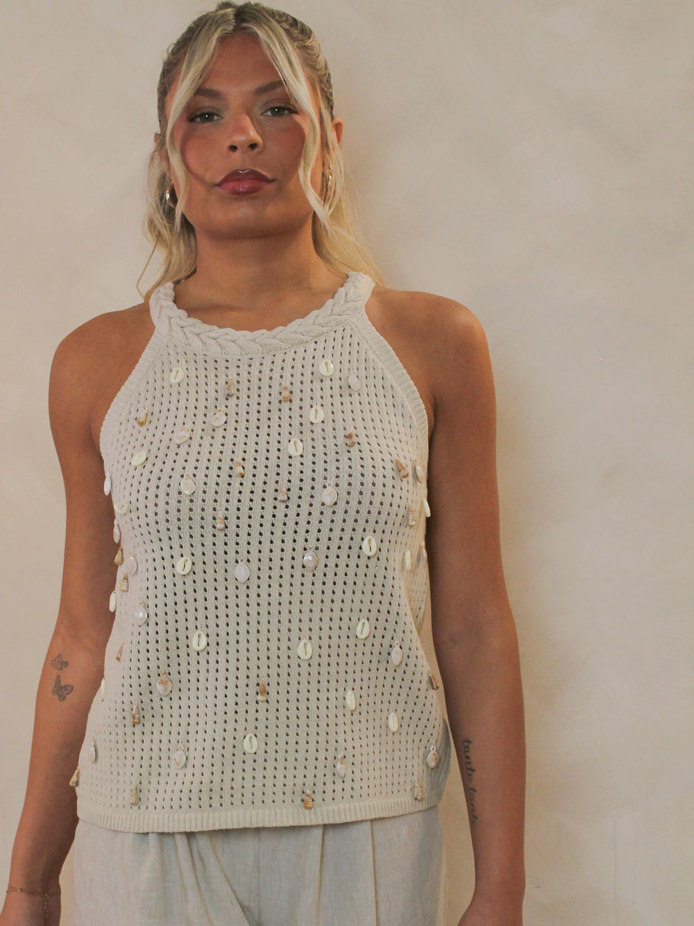 woman wearing a neutral knit tank with shell charms all over