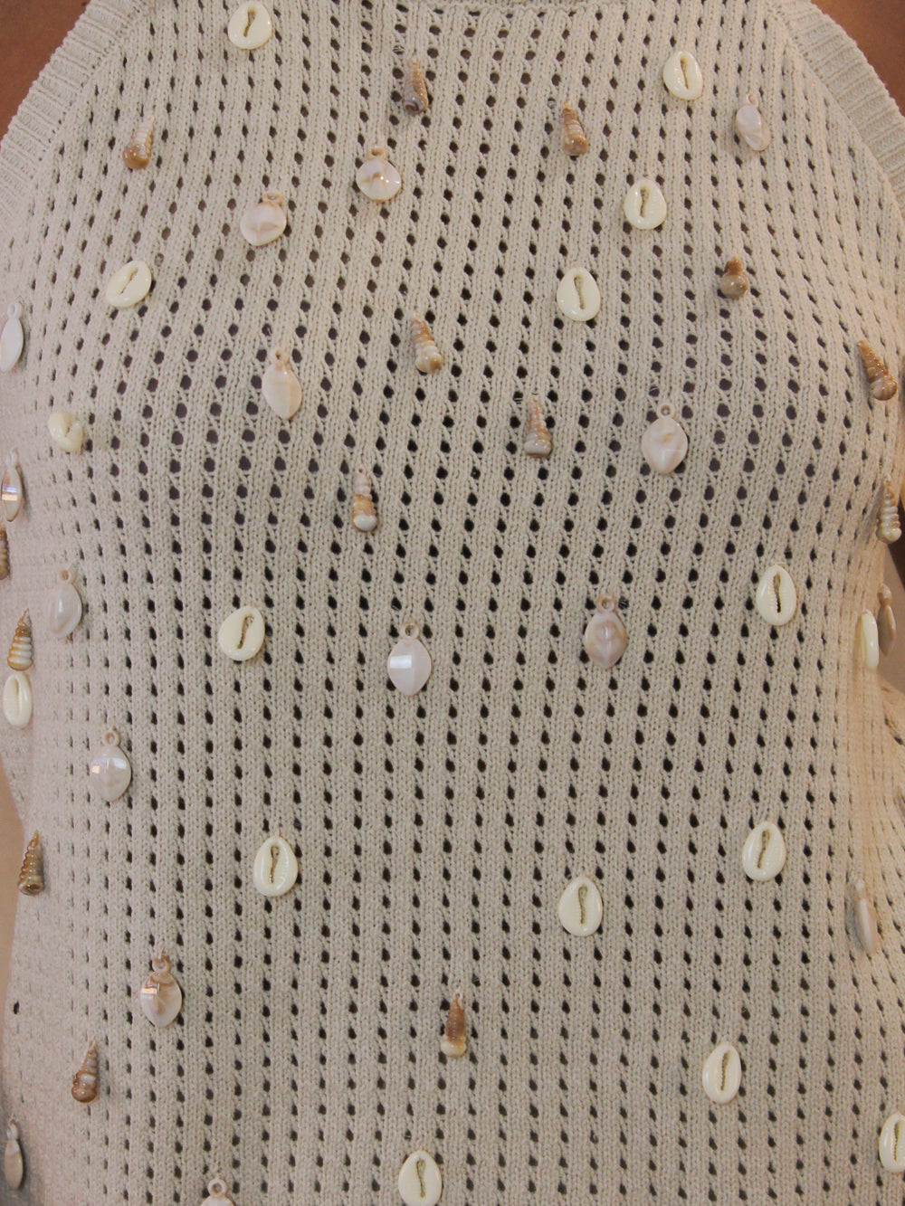 Beige crochet top with shell embellishments all over.