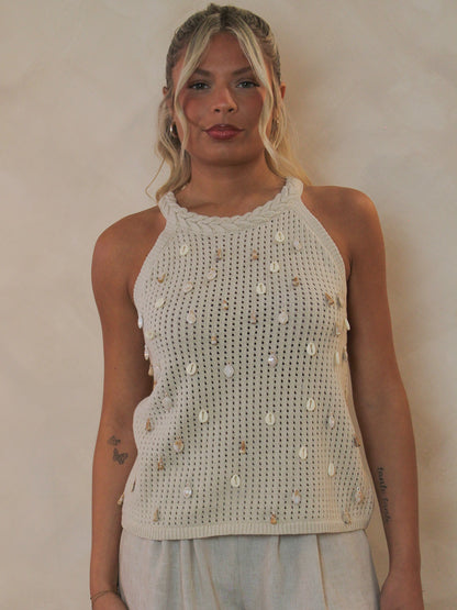 Woman wearing a open knit tank with shell embellishments all over