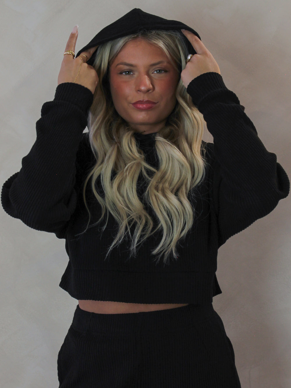 Model wearing a black ribbed long sleeve top with a hood