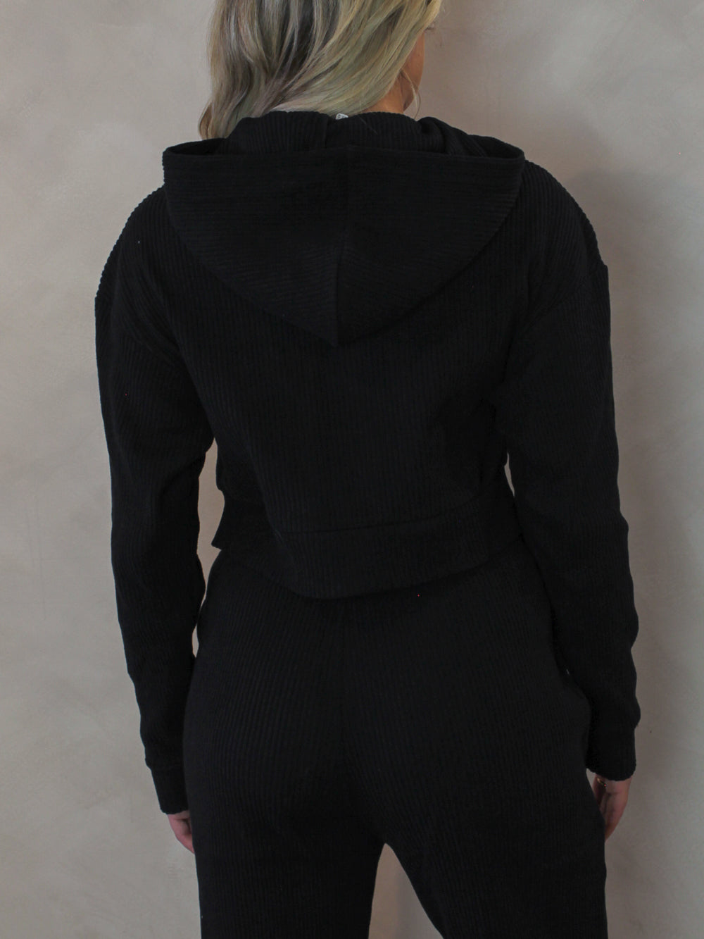 Back view of a black, ribbed, lounge top with hood 
