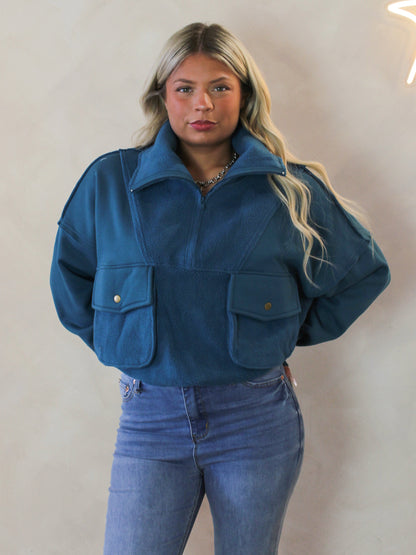 Model wearing a dark teal quarter zip pull over sweatshirt 