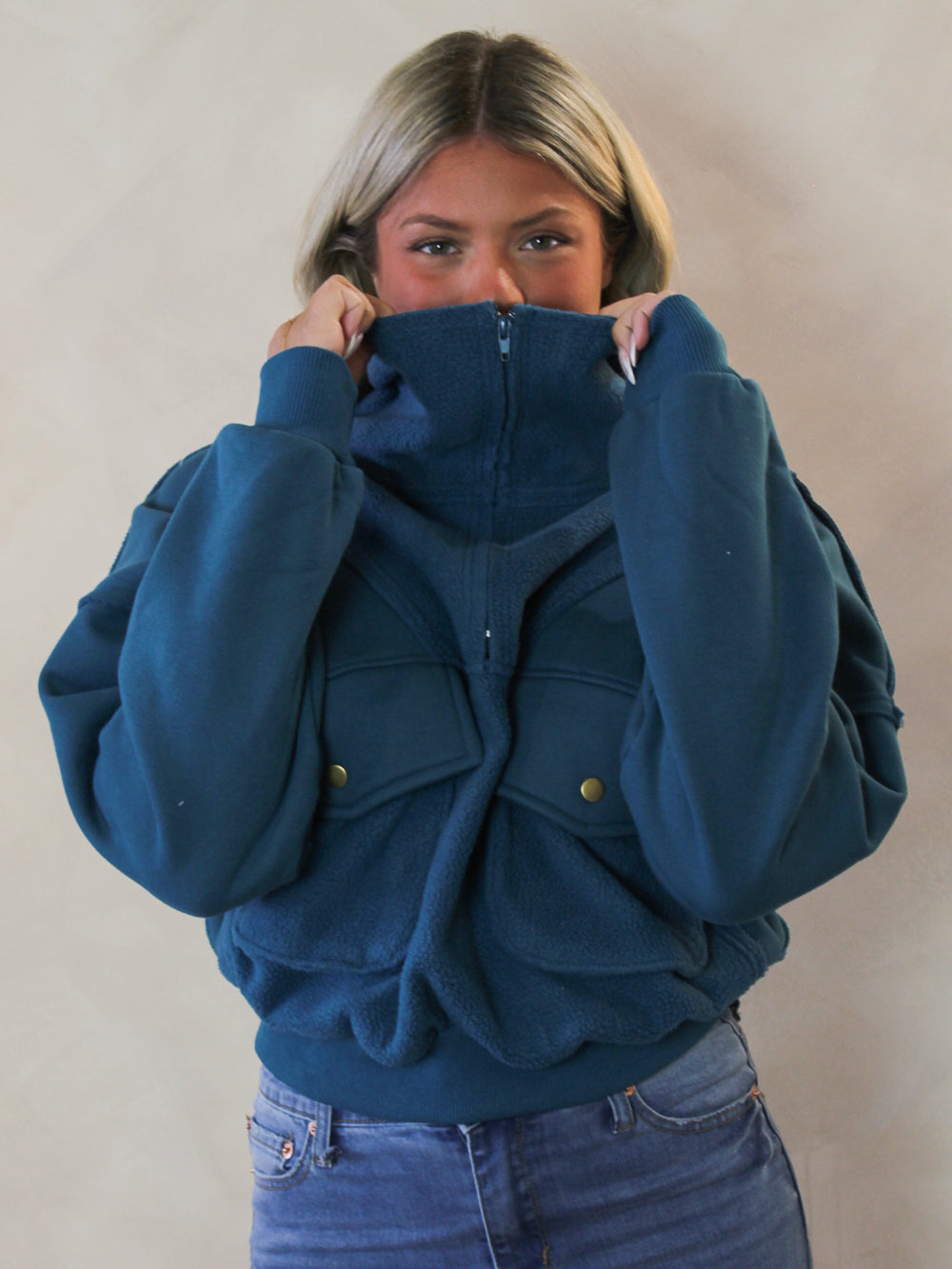Model wearing a teal pullover sweatshirt with funnel neck 