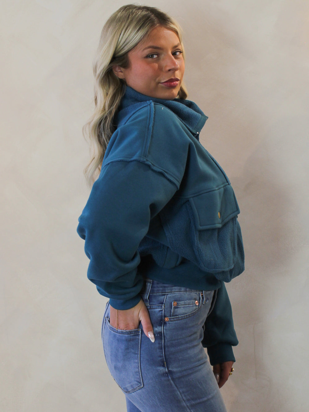 Model wearing a teal quarter zip pull over 