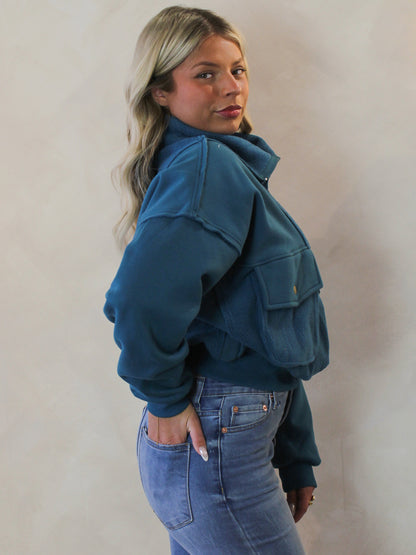 Model wearing a teal quarter zip pull over 