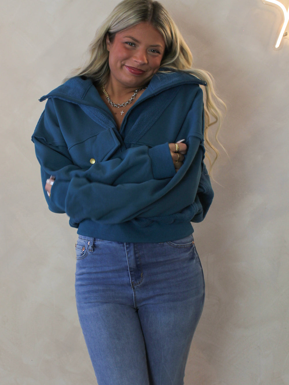Model wearing a cozy, teal zip up pull over sweatshirt 