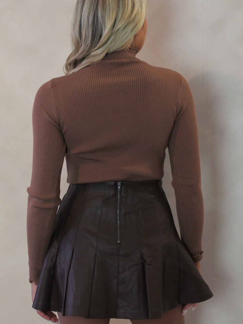 Model wearing a brown ribbed sweater with mock neck