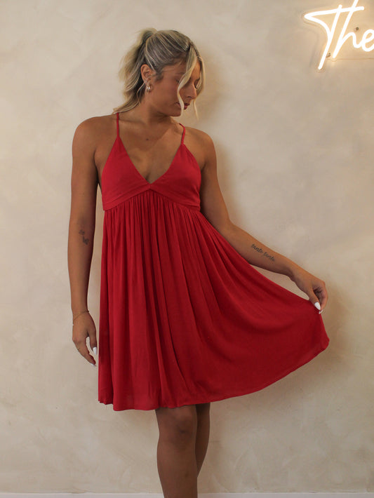Model wearing a short red dress with a flowing skirt and v-neckline