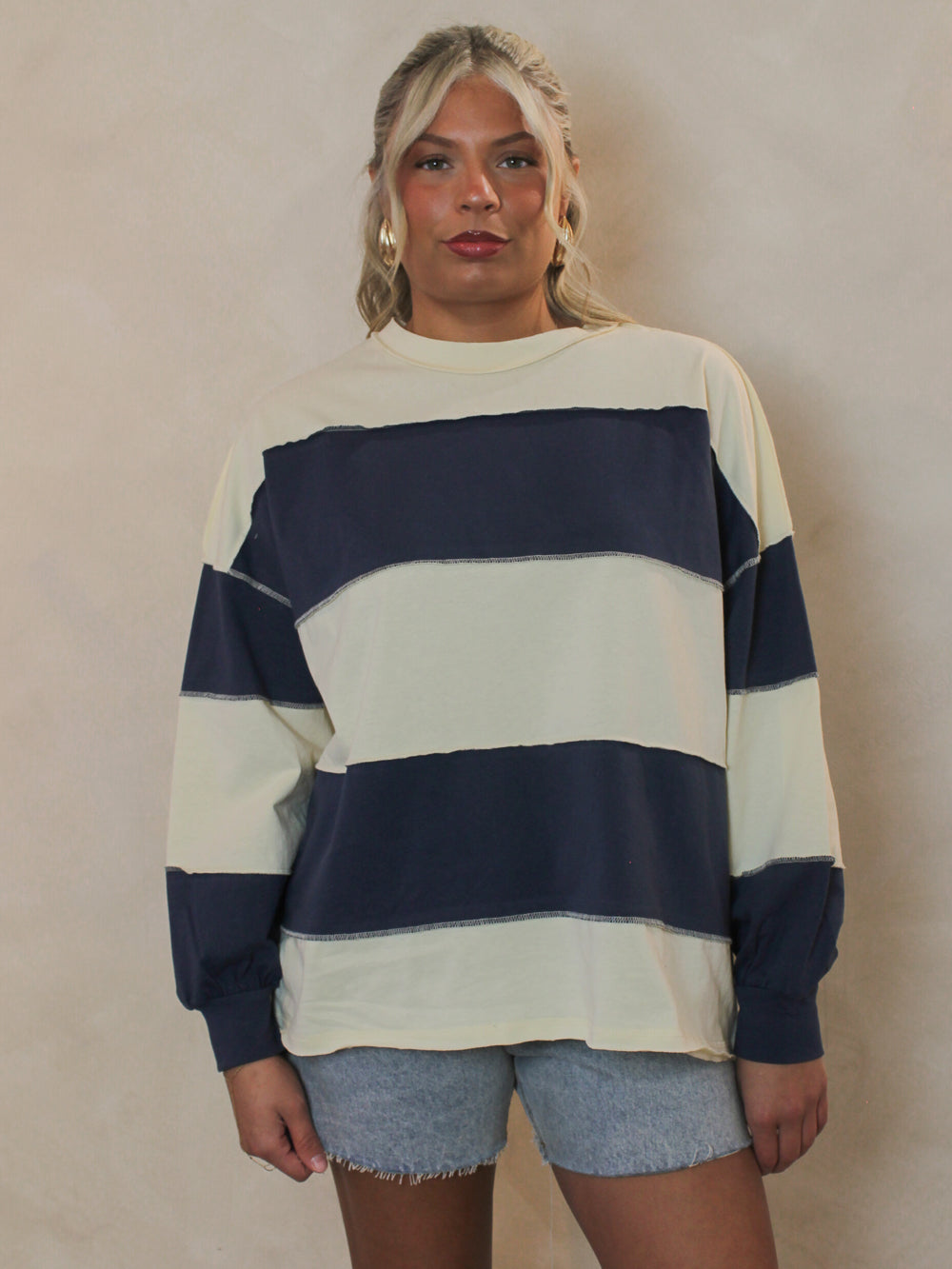 Girl wearing a blue and cream stripe long sleeve top with denim shorts
