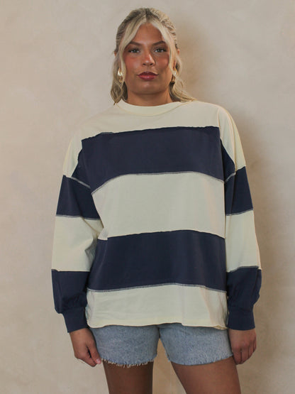 Girl wearing a blue and cream stripe long sleeve top with denim shorts
