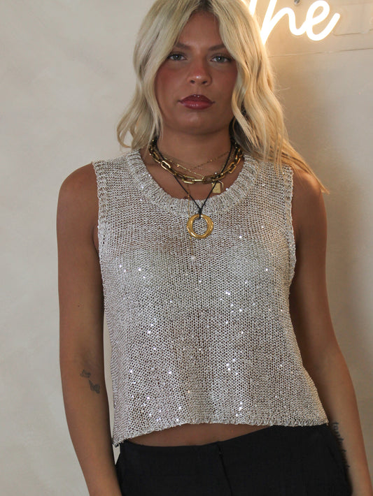 Woman wearing a sleeveless knit top with metallic and sequin details for holiday parties!