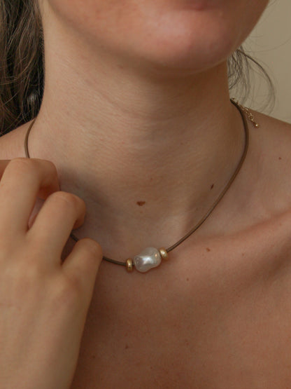 Brown cord necklace with a baroque pearl on a womens neck